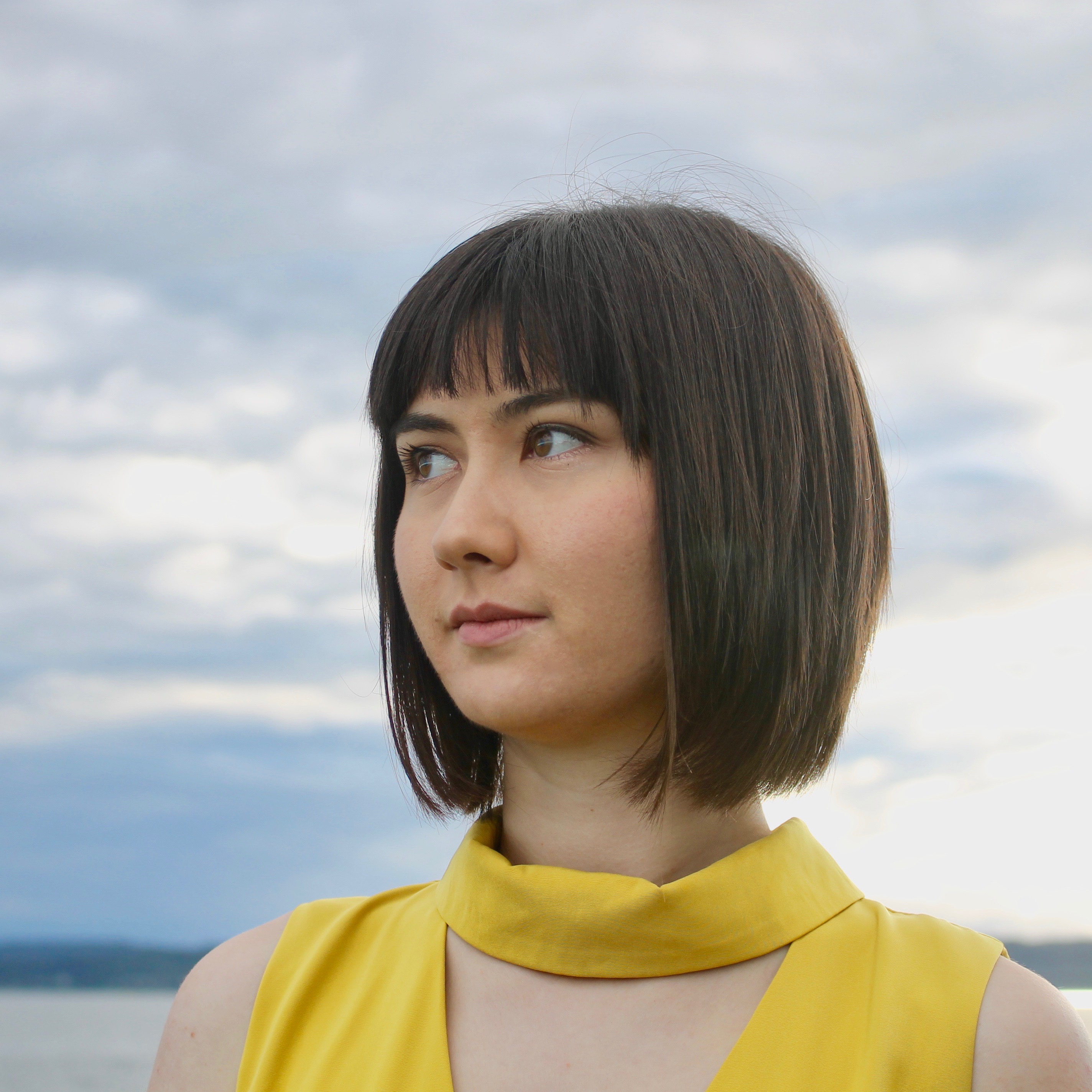 A headshot of Aya wearing a yellow dress at sunset